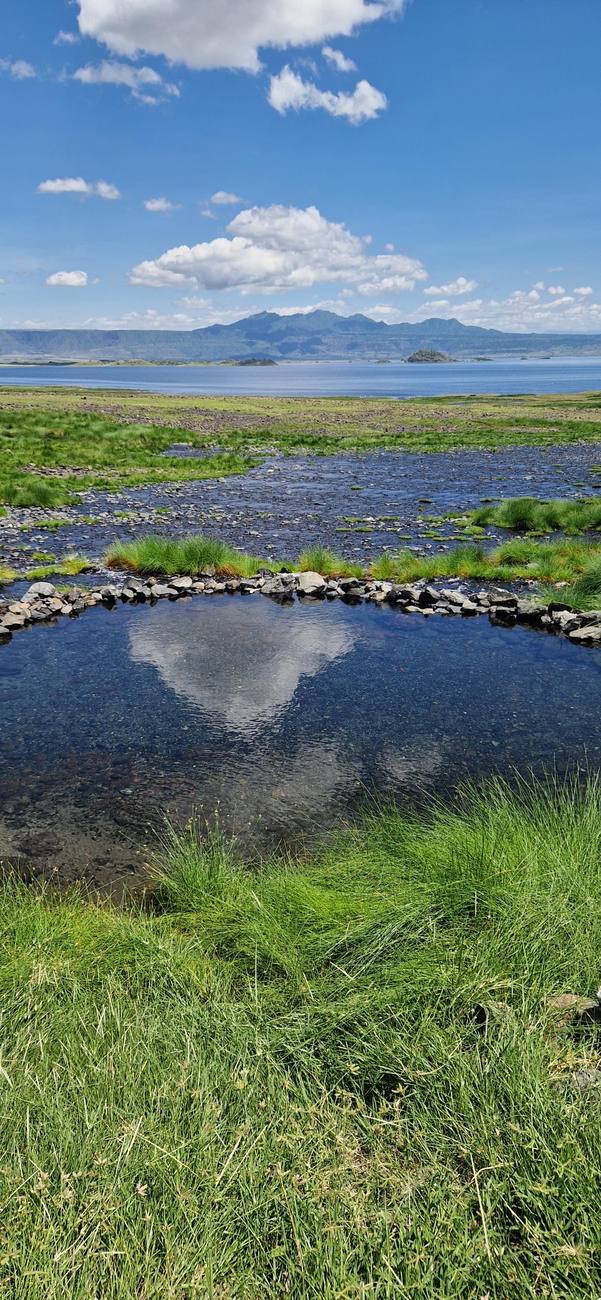 Une source d’eau chaude bordée de pierres, face au lac Natron